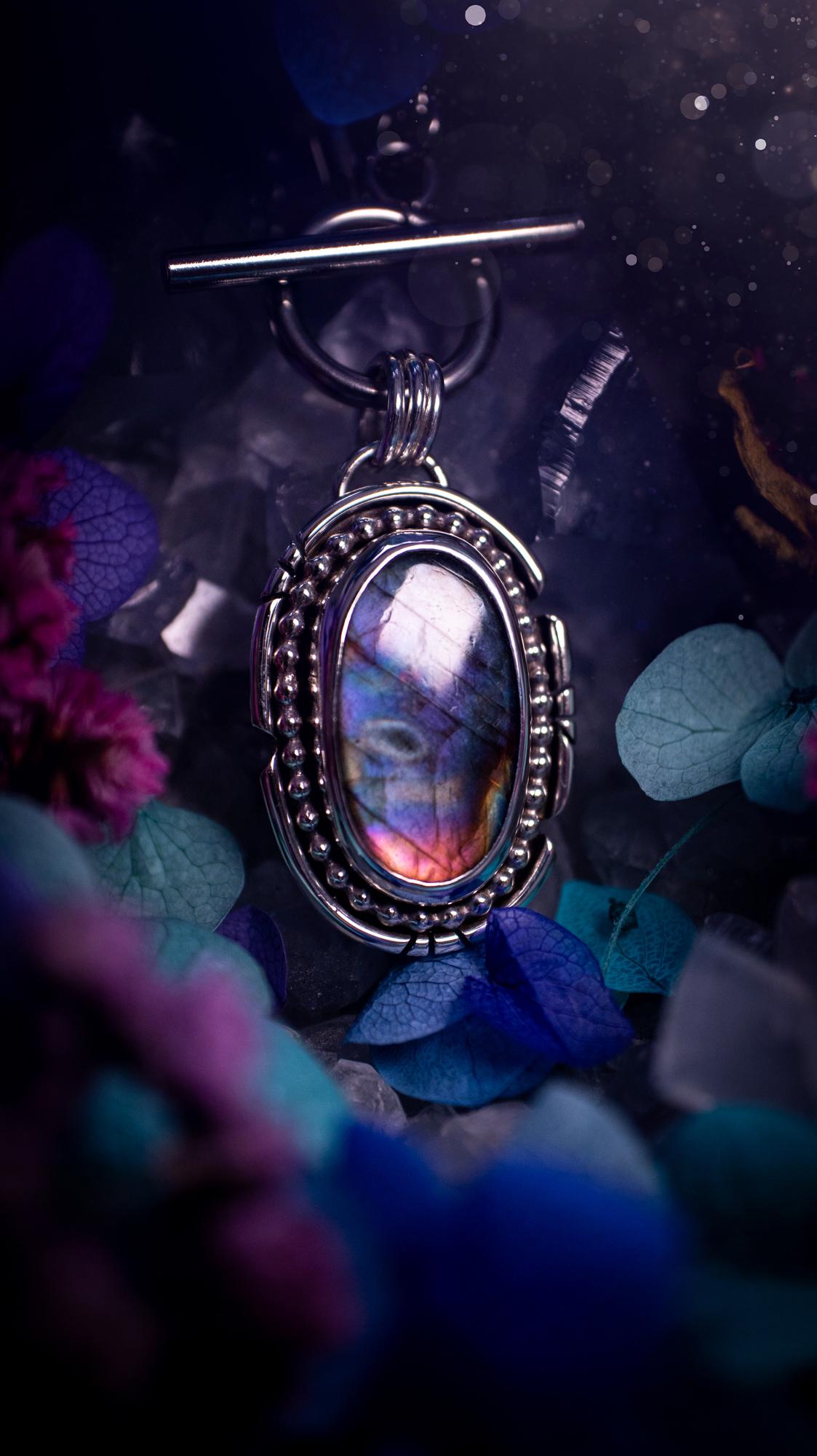 Beautifully handmade, amulet pendant necklace which features the most beautiful rainbow coloured, labradorite spectrolite crystal. This pendant has been handcrafted using a mix of fine and sterling silver. It features a smooth bezel with beaded, and hand carved smooth wire around the stone making this piece totally bespoke and one of a kind. The labradorite has an array of beautiful purples, blues and pinks. This pendant would be suitable for any crystal and jewellery lover, gothic and hippy!