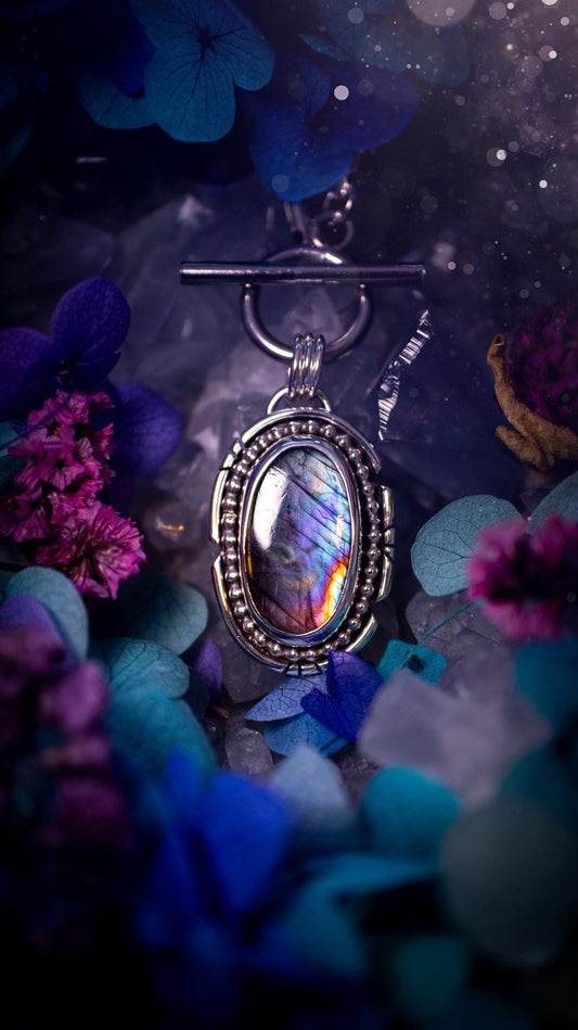 Beautifully handmade, amulet pendant necklace which features the most beautiful rainbow coloured, labradorite spectrolite crystal. This pendant has been handcrafted using a mix of fine and sterling silver. It features a smooth bezel with beaded, and hand carved smooth wire around the stone making this piece totally bespoke and one of a kind. The labradorite has an array of beautiful purples, blues and pinks. This pendant would be suitable for any crystal and jewellery lover, gothic and hippy!