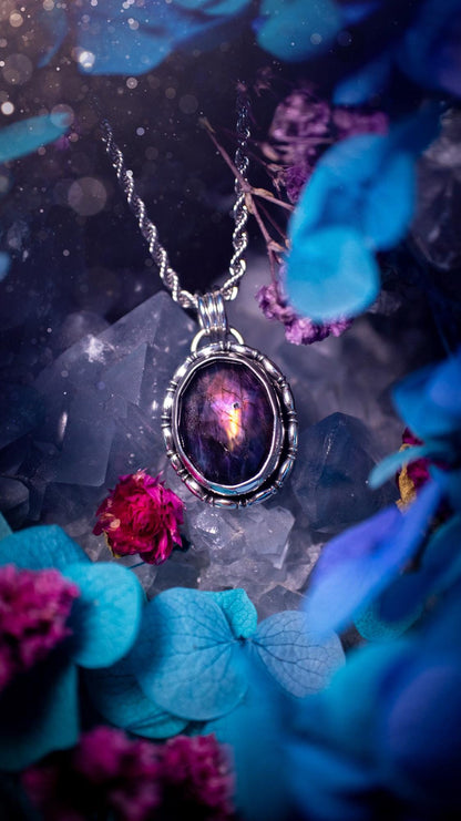 Beautifully handcrafted, rainbow labradorite crystal pendant necklace. This beautiful pendant has been crafted out of sterling and fine silver and features gothic bezel wire around the labradorite crystal. The labradorite in this piece is full of beautiful colours, purple, with a bit of orange! On top of the labradorite is Himalayan Quartz. This jewellery piece would be ideal for anyone who is a fan of jewellery and crystals, and would make the ideal gift. Full of witchy and gothic vibes!