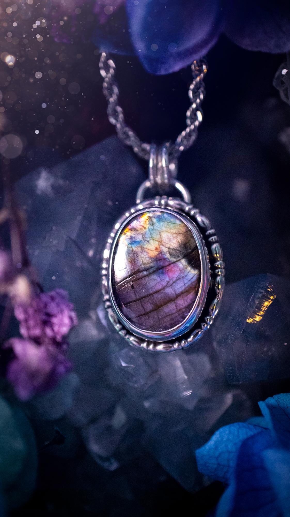 Beautifully handcrafted, rainbow labradorite crystal pendant necklace. This beautiful pendant has been crafted out of sterling and fine silver and features gothic bezel wire around the labradorite crystal. The labradorite in this piece is full of beautiful colours, purple, pinks and colours of the rainbow! This jewellery piece would be ideal for anyone who is a fan of jewellery and crystals, and would make the ideal gift. Full of witchy and gothic vibes!