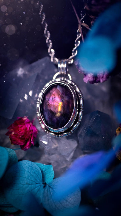 Beautifully handcrafted, rainbow labradorite crystal pendant necklace. This beautiful pendant has been crafted out of sterling and fine silver and features gothic bezel wire around the labradorite crystal. The labradorite in this piece is full of beautiful colours, purple, with a bit of orange! On top of the labradorite is Himalayan Quartz. This jewellery piece would be ideal for anyone who is a fan of jewellery and crystals, and would make the ideal gift. Full of witchy and gothic vibes!