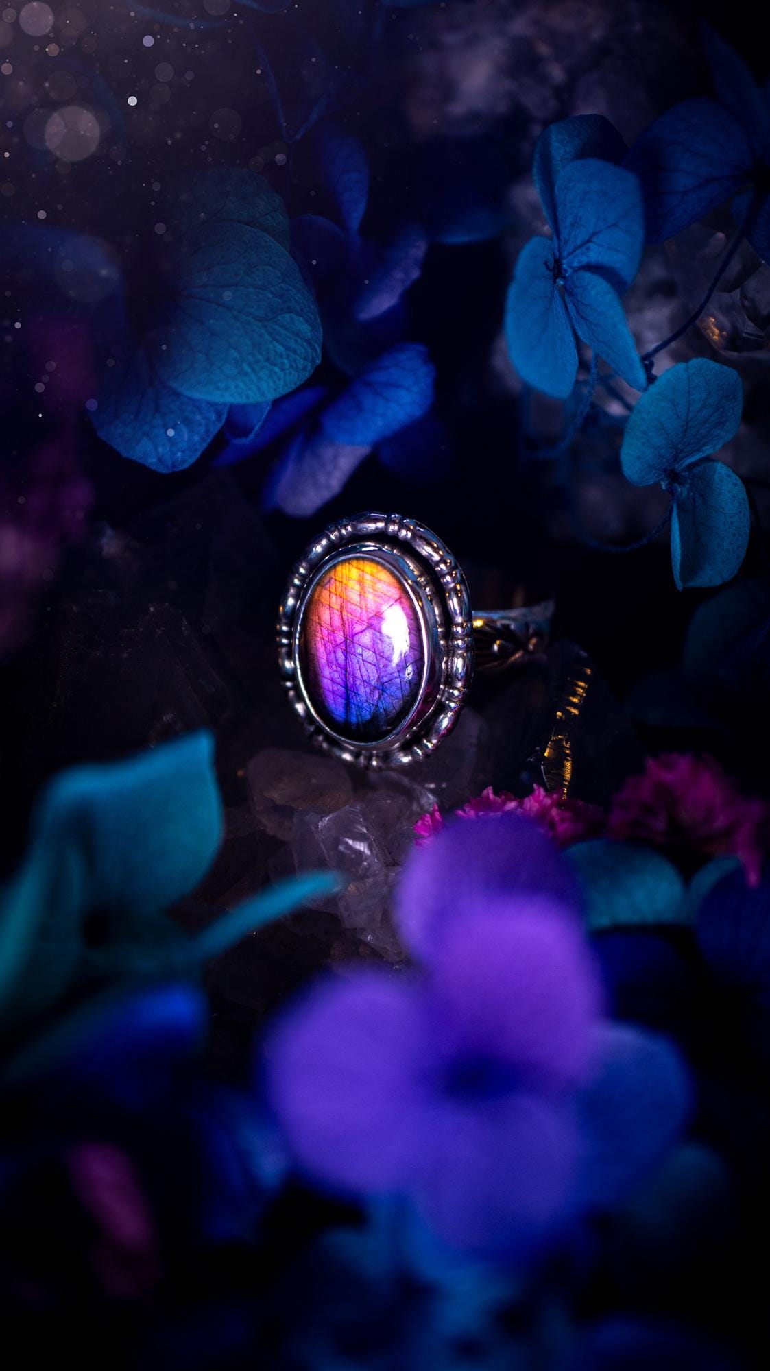 Handmade and very gothic, natural purple labradorite, sterling silver ring. This minimalist ring features a very pretty and flashy labradorite crystal that has a rich and vibrant purple colour. Around the crystal is a beautifully detail, gothic bezel that has been polished to a high lustre. The crystal is mounted on stamped ring shank. This ring would be ideal for anyone who loves jewellery and crystals, or who has a gothic and witchy style. A beautiful piece of jewellery to add to a collection