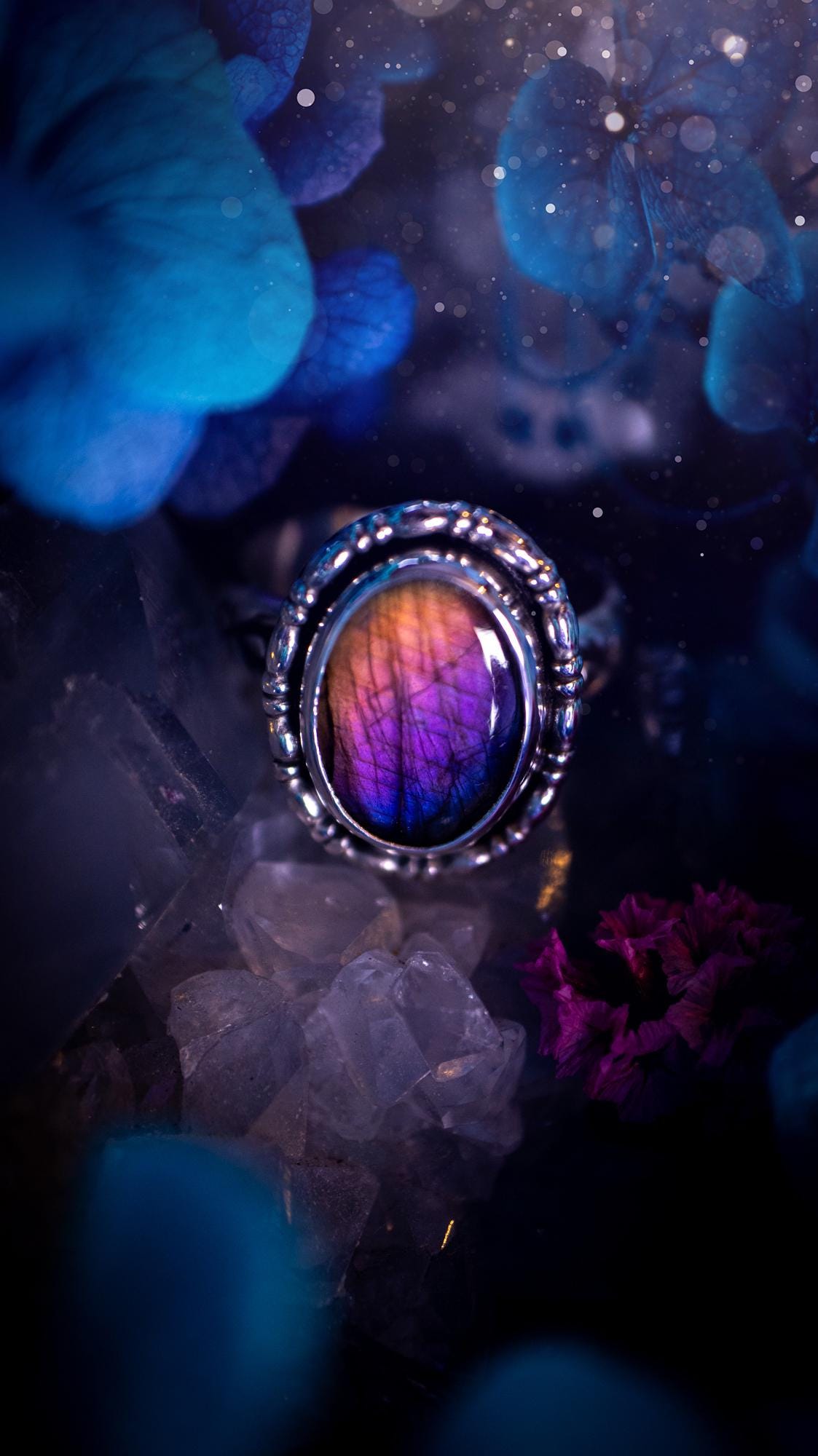 Handmade and very gothic, natural purple labradorite, sterling silver ring. This minimalist ring features a very pretty and flashy labradorite crystal that has a rich and vibrant purple colour. Around the crystal is a beautifully detail, gothic bezel that has been polished to a high lustre. The crystal is mounted on stamped ring shank. This ring would be ideal for anyone who loves jewellery and crystals, or who has a gothic and witchy style. A beautiful piece of jewellery to add to a collection