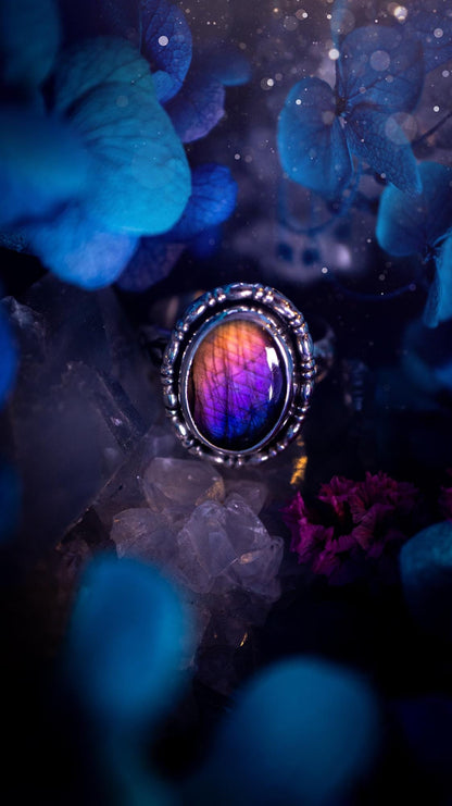 Handmade and very gothic, natural purple labradorite, sterling silver ring. This minimalist ring features a very pretty and flashy labradorite crystal that has a rich and vibrant purple colour. Around the crystal is a beautifully detail, gothic bezel that has been polished to a high lustre. The crystal is mounted on stamped ring shank. This ring would be ideal for anyone who loves jewellery and crystals, or who has a gothic and witchy style. A beautiful piece of jewellery to add to a collection