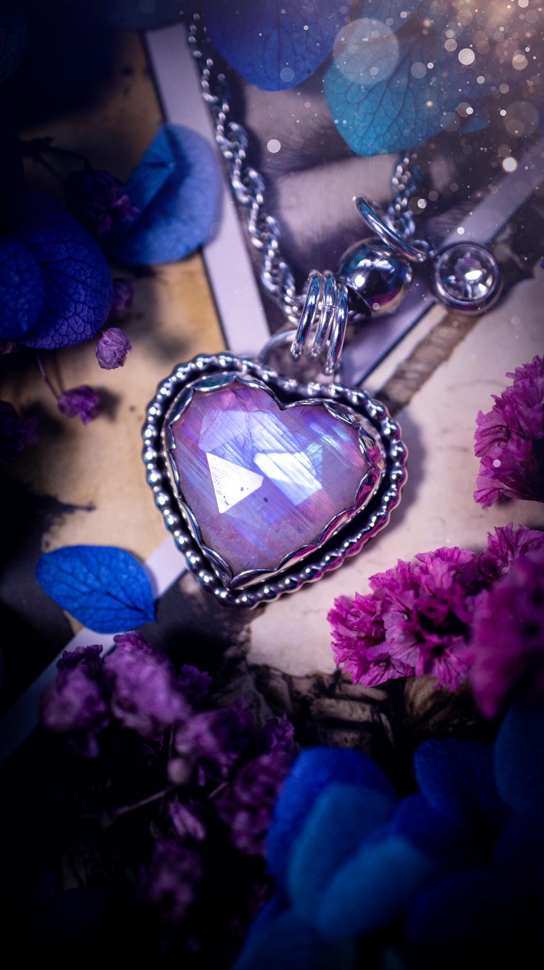 Handmade and bespoke, pink rainbow moonstone heart, sterling silver pendant necklace. This lovely pendant feature a very high quality rainbow moonstone that is full of gorgeous pink and blue flash. This unusual pink colour has been created by using materials under the stone so the pink hue shines through with the iridescence of the moonstone. Made from fine and sterling silver. An ideal piece for any crystal and jewellery lover. Moonstone is the birthstone for June. Unique gothic jewellery