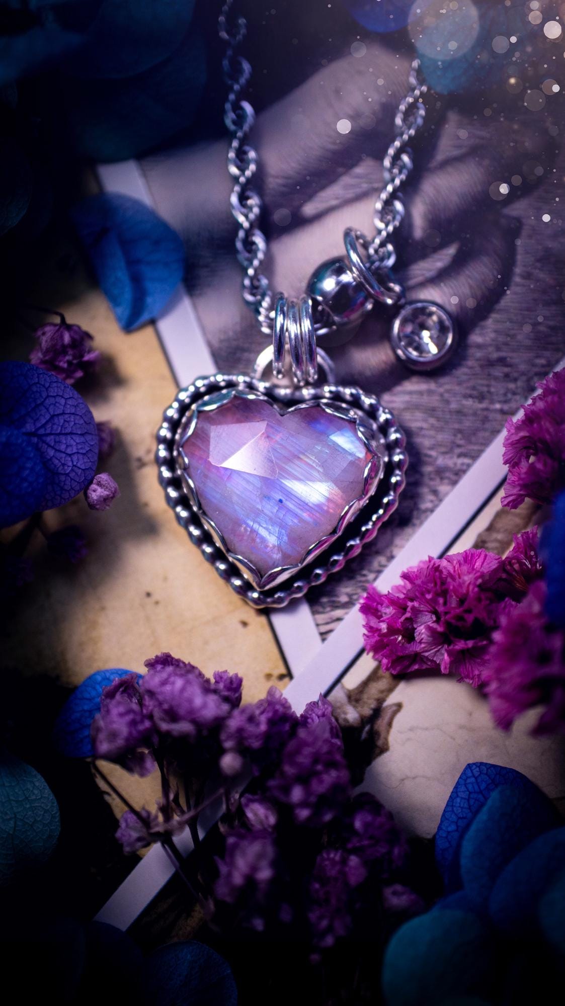 Handmade and bespoke, pink rainbow moonstone heart, sterling silver pendant necklace. This lovely pendant feature a very high quality rainbow moonstone that is full of gorgeous pink and blue flash. This unusual pink colour has been created by using materials under the stone so the pink hue shines through with the iridescence of the moonstone. Made from fine and sterling silver. An ideal piece for any crystal and jewellery lover. Moonstone is the birthstone for June. Unique gothic jewellery