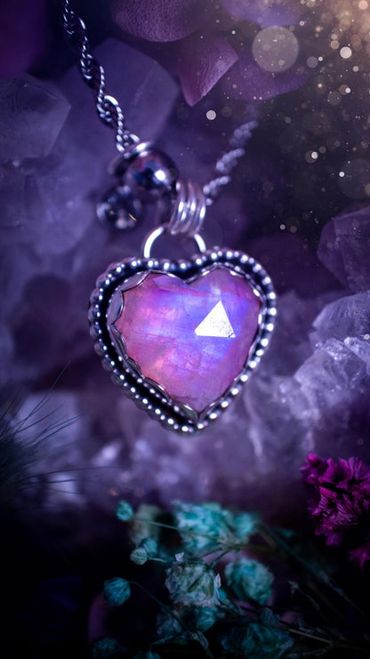 Handmade and bespoke, pink rainbow moonstone heart, sterling silver pendant necklace. This lovely pendant feature a very high quality rainbow moonstone that is full of gorgeous pink and blue flash. This unusual pink colour has been created by using materials under the stone so the pink hue shines through with the iridescence of the moonstone. Made from fine and sterling silver. An ideal piece for any crystal and jewellery lover. Moonstone is the birthstone for June. Unique gothic jewellery
