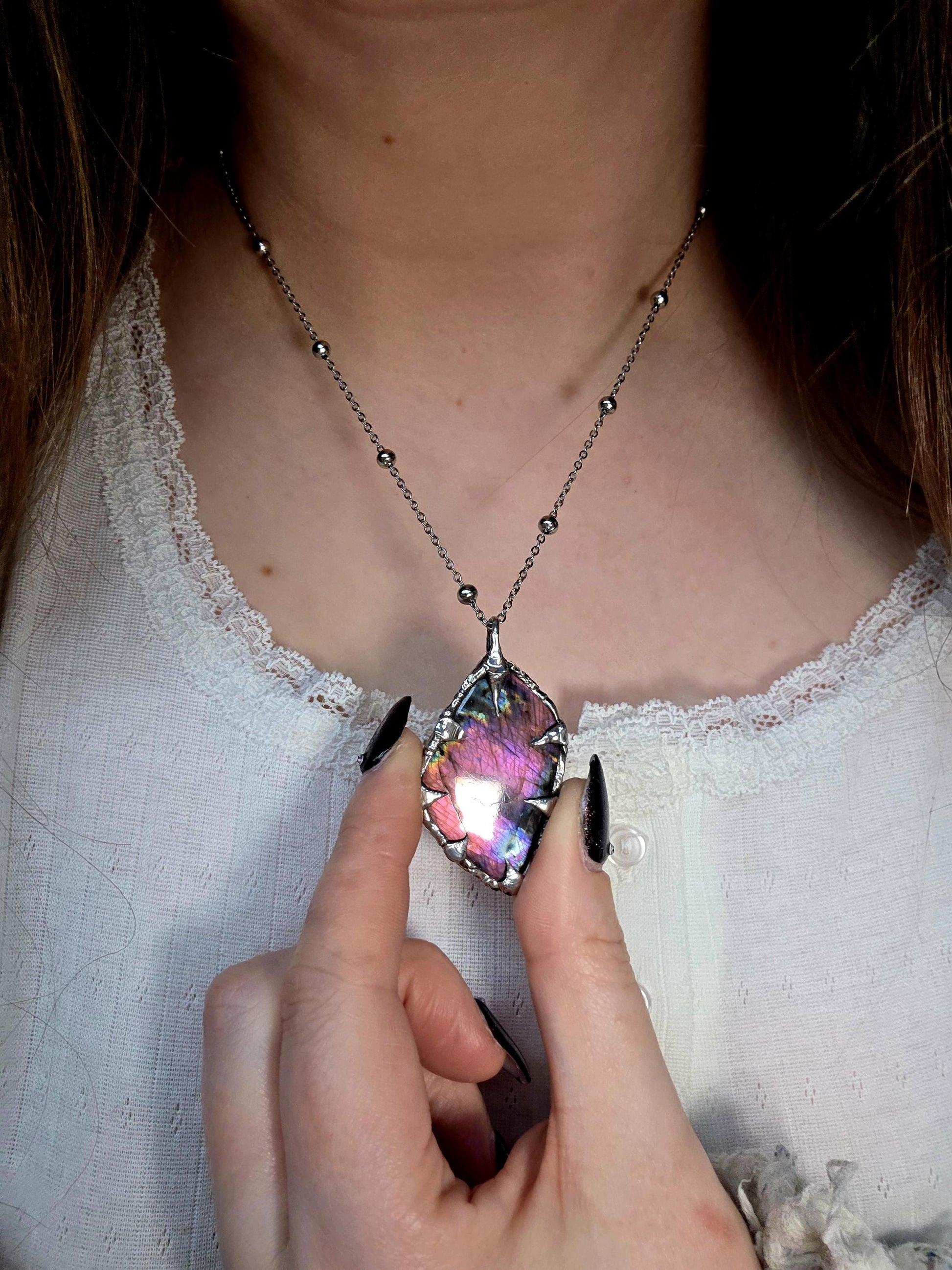 Beautiful and bold, soft soldered, purple and pink Labradorite pendant necklace. This pendant necklace has been handmade using the soft solder method, using lead free solder that contains silver and polished to a high lustre. Featuring a very pretty statement Labradorite crystal that is full of beautiful purples, pinks, blues and orange, with different flashes from different angles. This piece would but suitable for anyone who loves jewellery, crystals, and a gothic aesthetic.