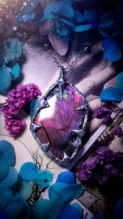 Beautiful and bold, soft soldered, purple and pink Labradorite pendant necklace. This pendant necklace has been handmade using the soft solder method, using lead free solder that contains silver and polished to a high lustre. Featuring a very pretty statement Labradorite crystal that is full of beautiful purples, pinks, blues and orange, with different flashes from different angles. This piece would but suitable for anyone who loves jewellery, crystals, and a gothic aesthetic.