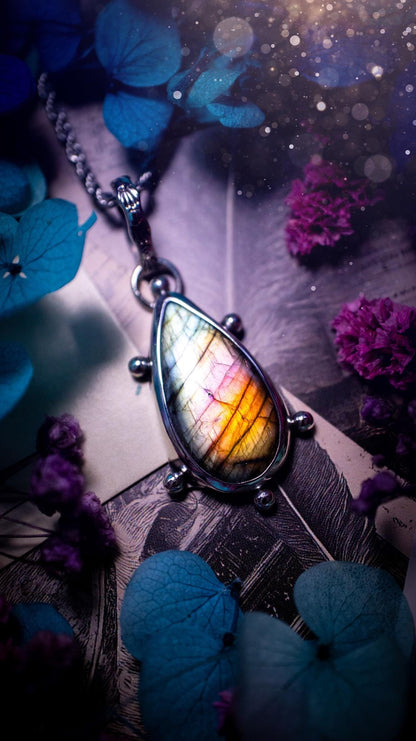 One of a kind and very unique, rainbow labradorite, crystal pendant necklace. This bohemian style pendant necklace has been handcrafted using a mix of fine and sterling silver. Featuring a rare rainbow coloured labradorite that has such a strong intense flash full of beautiful hue. Around the smooth bezel is small silver ball details, and a bohemian stamped pattern bail. This pendant necklace would be ideal for anyone who loves crystal and jewellery. One of pieces of jewellery for the soul.