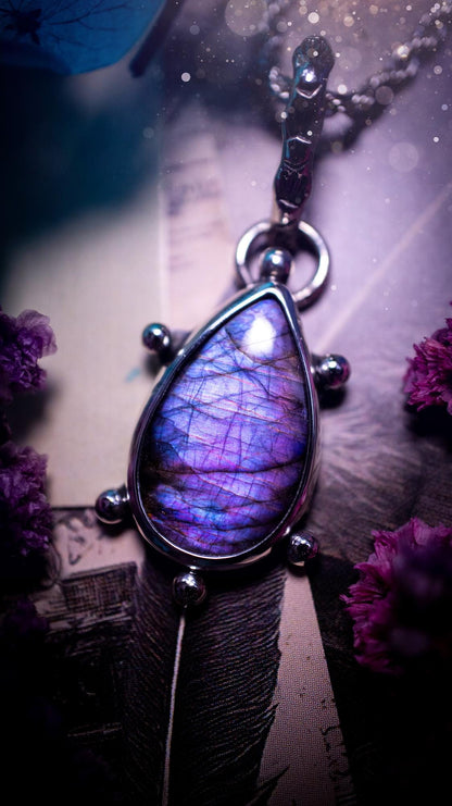 One of a kind and very unique, purple and pink labradorite, crystal pendant necklace. This bohemian style pendant necklace has been handcrafted using a mix of fine and sterling silver. Featuring a purple coloured labradorite that has such a strong intense flash full of beautiful hue. Around the smooth bezel is small silver ball details, and a bohemian stamped pattern bail. This pendant necklace would be ideal for anyone who loves crystal and jewellery. One of pieces of jewellery for the soul.