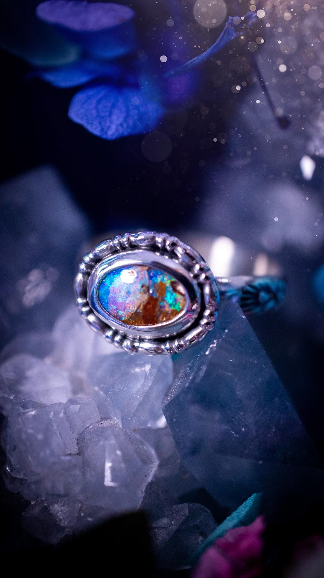 One of a kind and handmade, Australian boulder opal, bohemian ring. This stunning ring has been handcrafted using a mix of fine and sterling silver. Featuring a small, yet totally stunning and vibrant Australian boulder opal full of blues, purples, and green sparkles. Around the smooth bezel is some pretty gallery wire. The ring shank has also been stamped with a bohemian pattern. This one off piece is ideal for any crystal and jewellery lover who is seeking a piece that has no other the same!