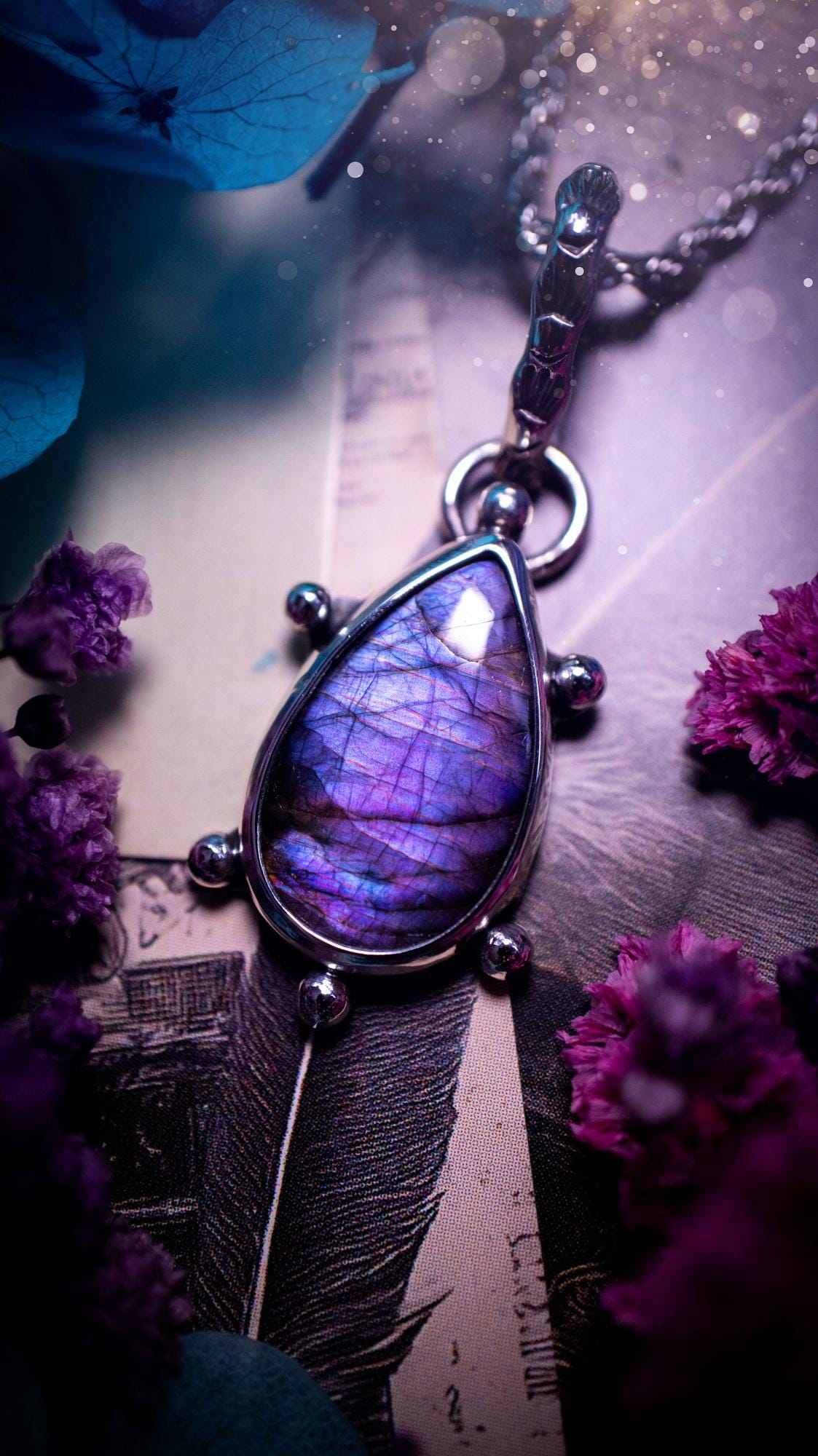 One of a kind and very unique, purple and pink labradorite, crystal pendant necklace. This bohemian style pendant necklace has been handcrafted using a mix of fine and sterling silver. Featuring a purple coloured labradorite that has such a strong intense flash full of beautiful hue. Around the smooth bezel is small silver ball details, and a bohemian stamped pattern bail. This pendant necklace would be ideal for anyone who loves crystal and jewellery. One of pieces of jewellery for the soul.