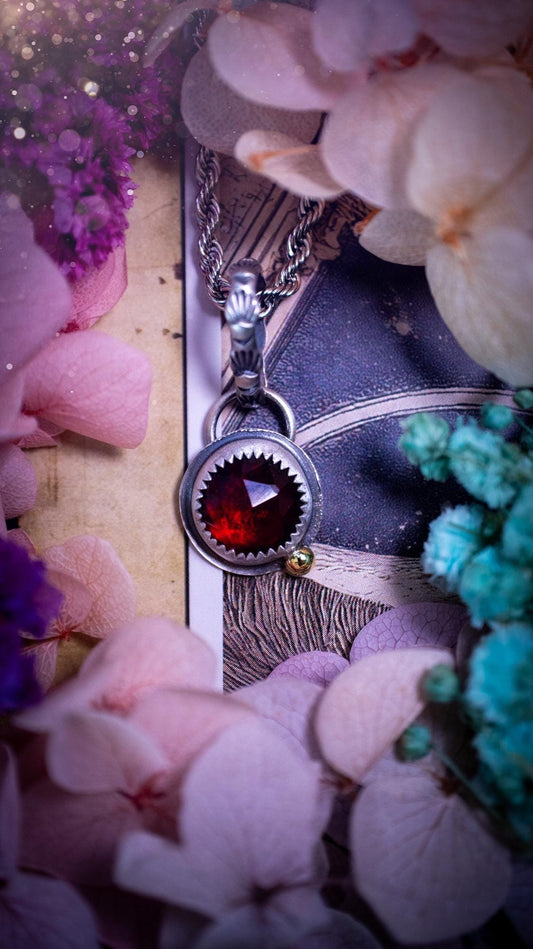 Handmade garnet pendant set in sterling silver with a satin brushed finish. The deep red natural garnet gemstone has a rich, wine-toned colour that catches the light beautifully. Finished with a polished brass golden ball accent and a decorative patterned bail. Gothic, bohemian and witchy style crystal jewellery, perfect as a meaningful gift or elegant everyday statement piece.