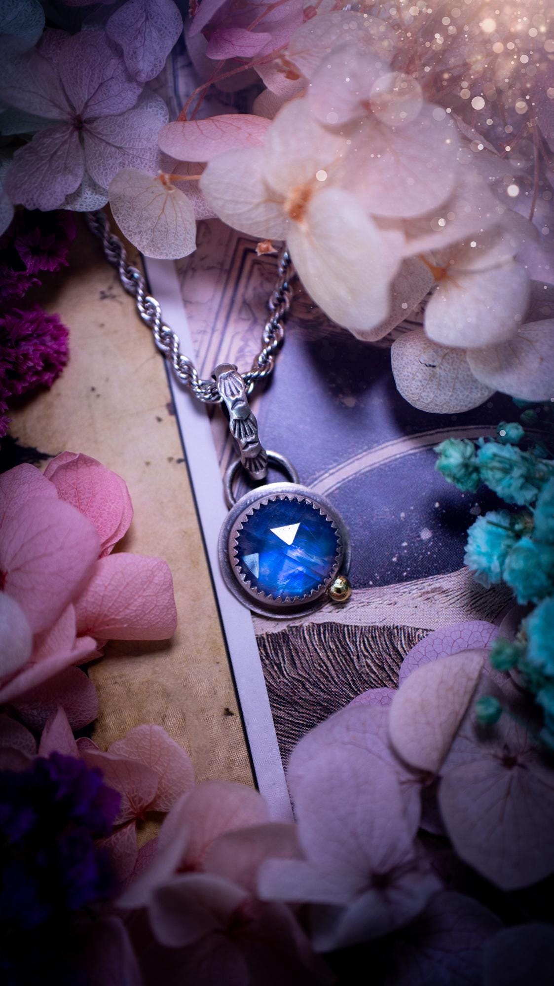 Handmade rainbow moonstone pendant set in sterling silver with a satin brushed finish. The natural moonstone gemstone shows a soft blue flash that shifts beautifully in the light. Finished with a polished brass golden ball accent and a decorative patterned bail. Bohemian, gothic and witchy style crystal jewellery, perfect as a unique gift or elegant everyday piece.