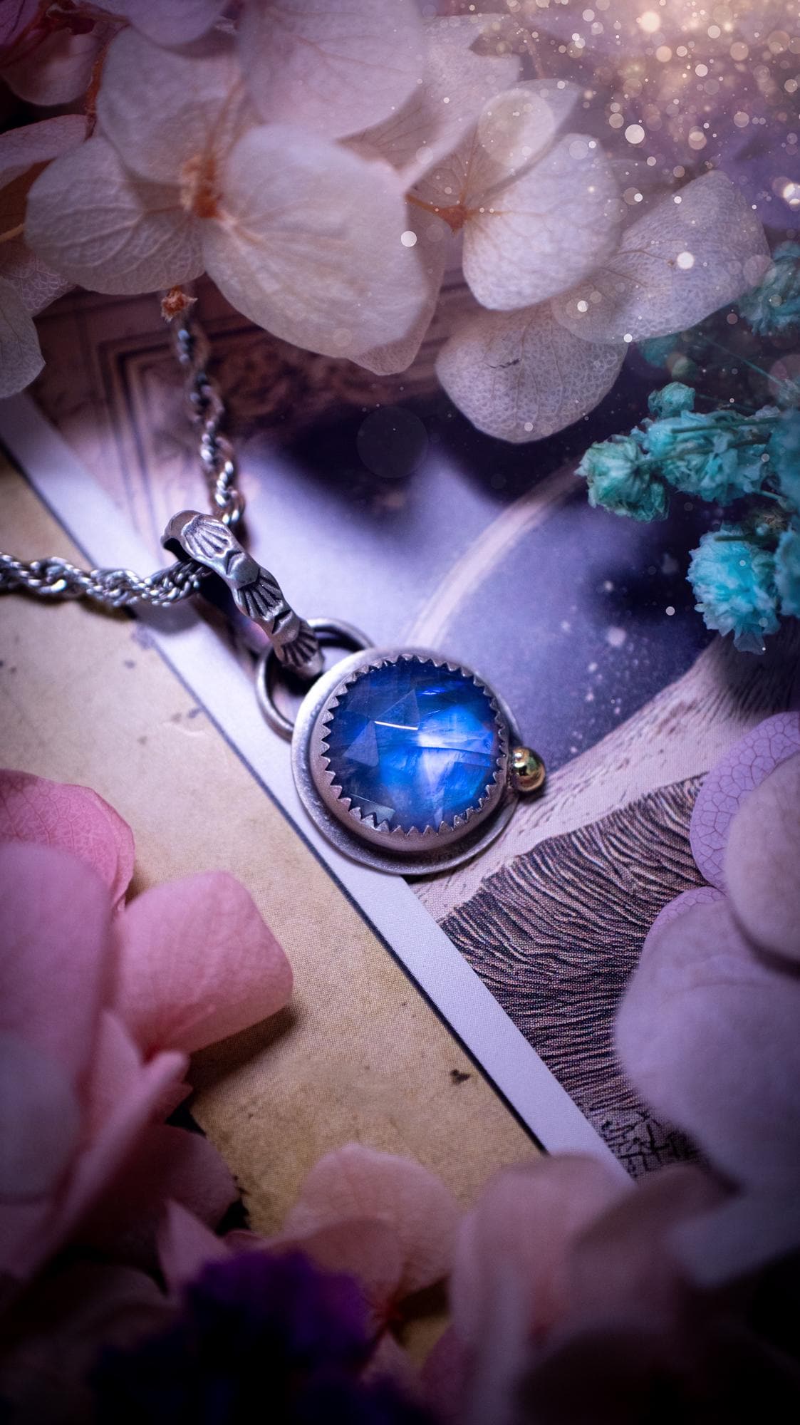 Handmade rainbow moonstone pendant set in sterling silver with a satin brushed finish. The natural moonstone gemstone shows a soft blue flash that shifts beautifully in the light. Finished with a polished brass golden ball accent and a decorative patterned bail. Bohemian, gothic and witchy style crystal jewellery, perfect as a unique gift or elegant everyday piece.