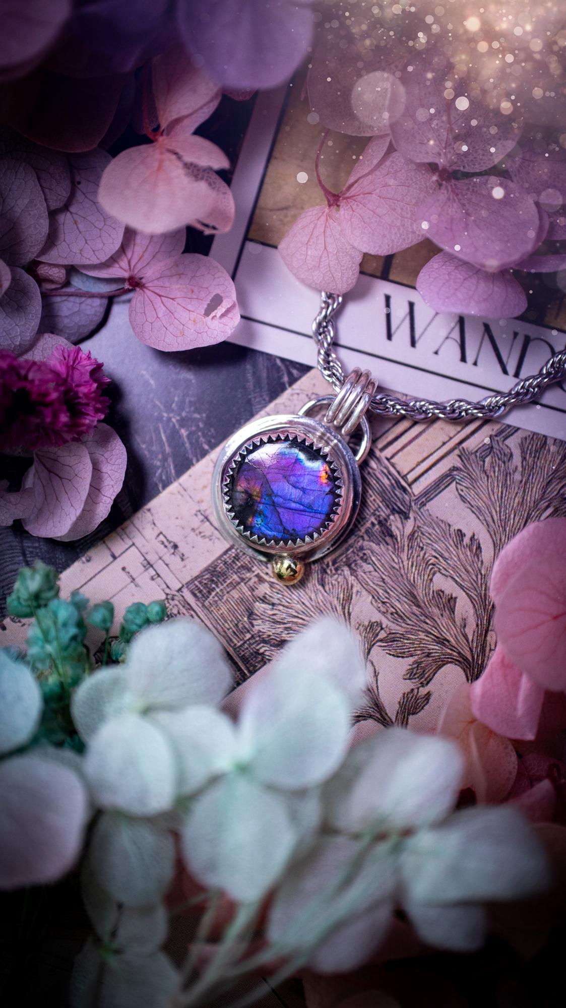 Handmade purple, rainbow labradorite pendant set in sterling silver with a high polished finish. The natural labradorite gemstone shows flashes of blue, gold and rainbow tones depending on the light. Features a polished brass golden ball accent and multi ring bail. Bohemian, gothic and witchy style crystal jewellery, perfect as a unique gift or everyday statement piece.