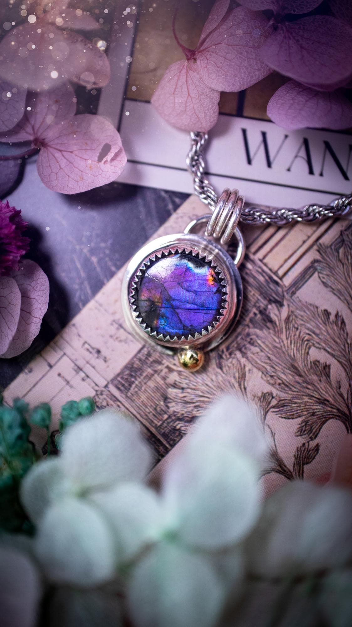 Handmade purple, rainbow labradorite pendant set in sterling silver with a high polished finish. The natural labradorite gemstone shows flashes of blue, gold and rainbow tones depending on the light. Features a polished brass golden ball accent and multi ring bail. Bohemian, gothic and witchy style crystal jewellery, perfect as a unique gift or everyday statement piece.