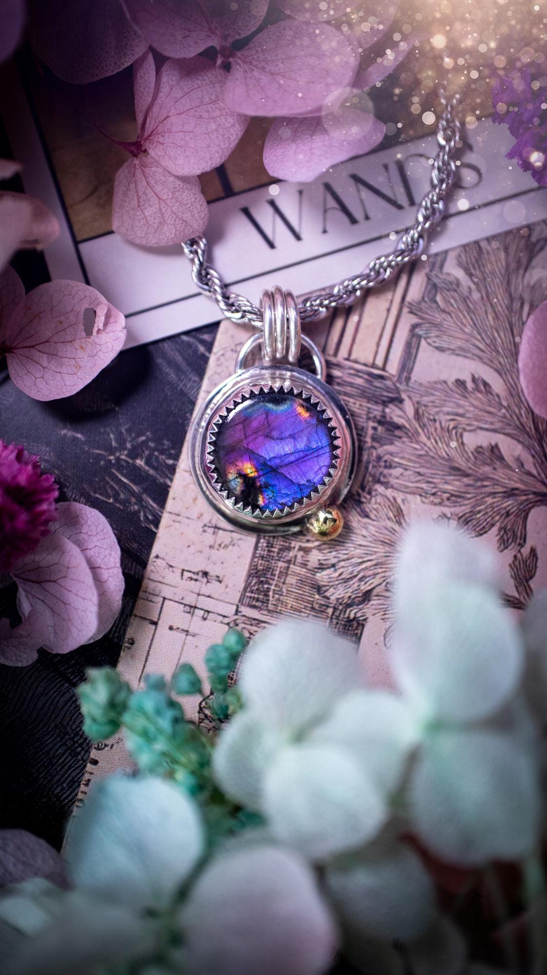 Handmade purple, rainbow labradorite pendant set in sterling silver with a high polished finish. The natural labradorite gemstone shows flashes of blue, gold and rainbow tones depending on the light. Features a polished brass golden ball accent and multi ring bail. Bohemian, gothic and witchy style crystal jewellery, perfect as a unique gift or everyday statement piece.