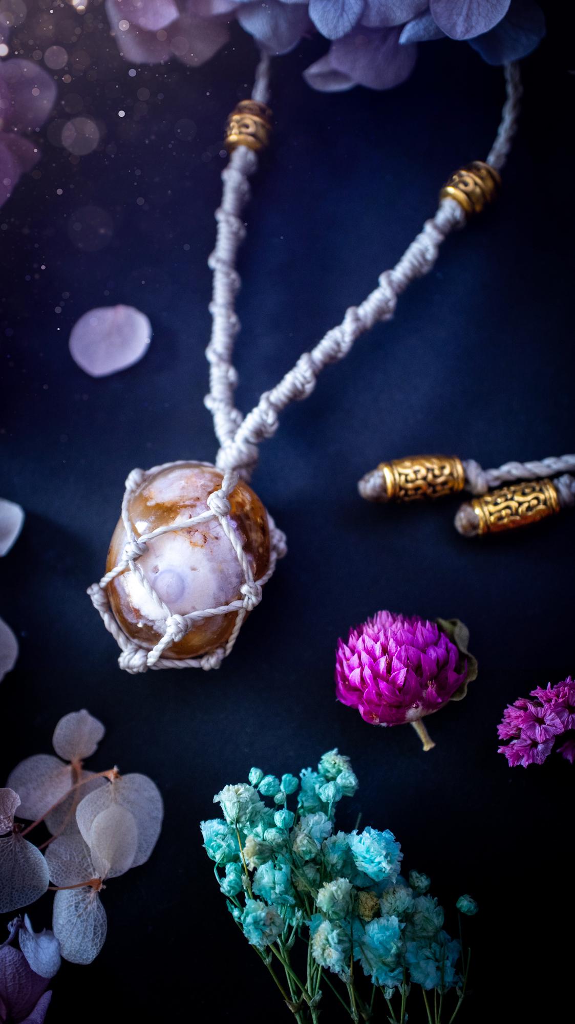 Handmade flower agate macrame pendant necklace featuring a natural patterned flower agate crystal in a woven caged design. Made using high quality Linhasita waxed cord with gold boho style accent beads. Bohemian, earthy and witchy inspired crystal jewellery, perfect for everyday wear or as a meaningful spiritual gift for crystal lovers.
