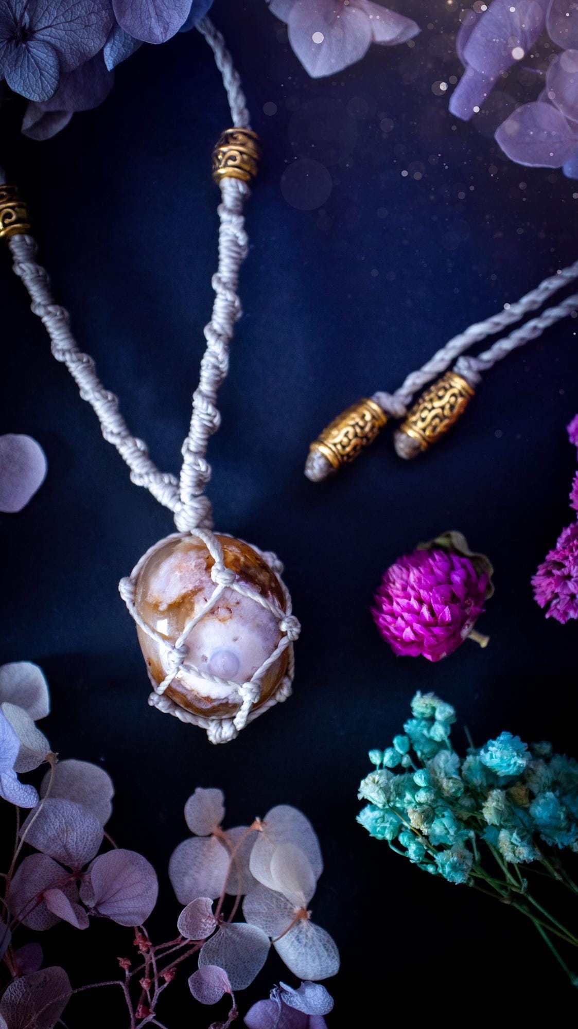 Handmade flower agate macrame pendant necklace featuring a natural patterned flower agate crystal in a woven caged design. Made using high quality Linhasita waxed cord with gold boho style accent beads. Bohemian, earthy and witchy inspired crystal jewellery, perfect for everyday wear or as a meaningful spiritual gift for crystal lovers.