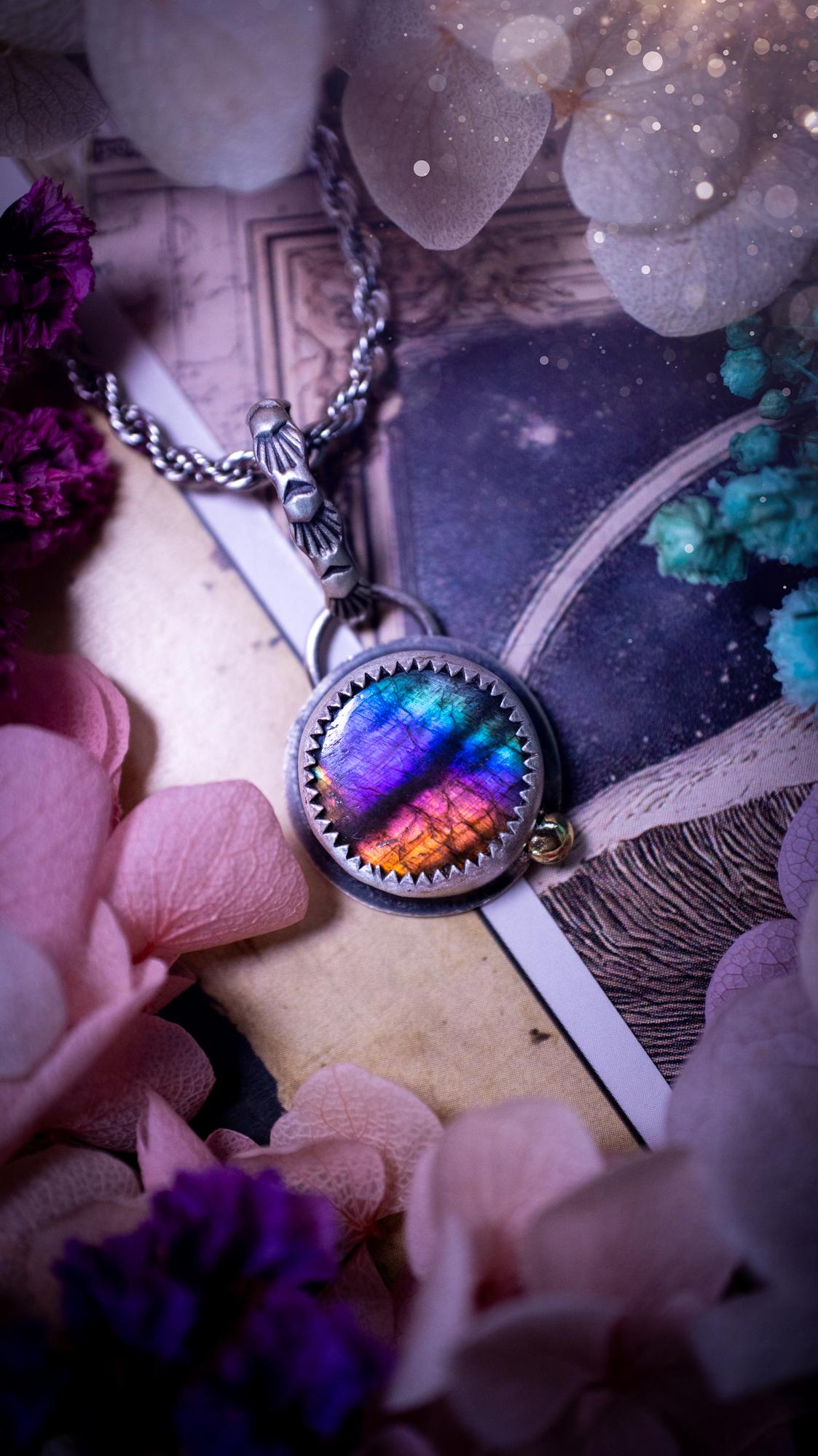 Handmade rainbow labradorite pendant set in sterling silver with a satin brushed finish. The natural labradorite gemstone shows flashes of blue, gold and rainbow tones depending on the light. Features a polished brass golden ball accent and a decorative patterned bail. Bohemian, gothic and witchy style crystal jewellery, perfect as a unique gift or everyday statement piece.