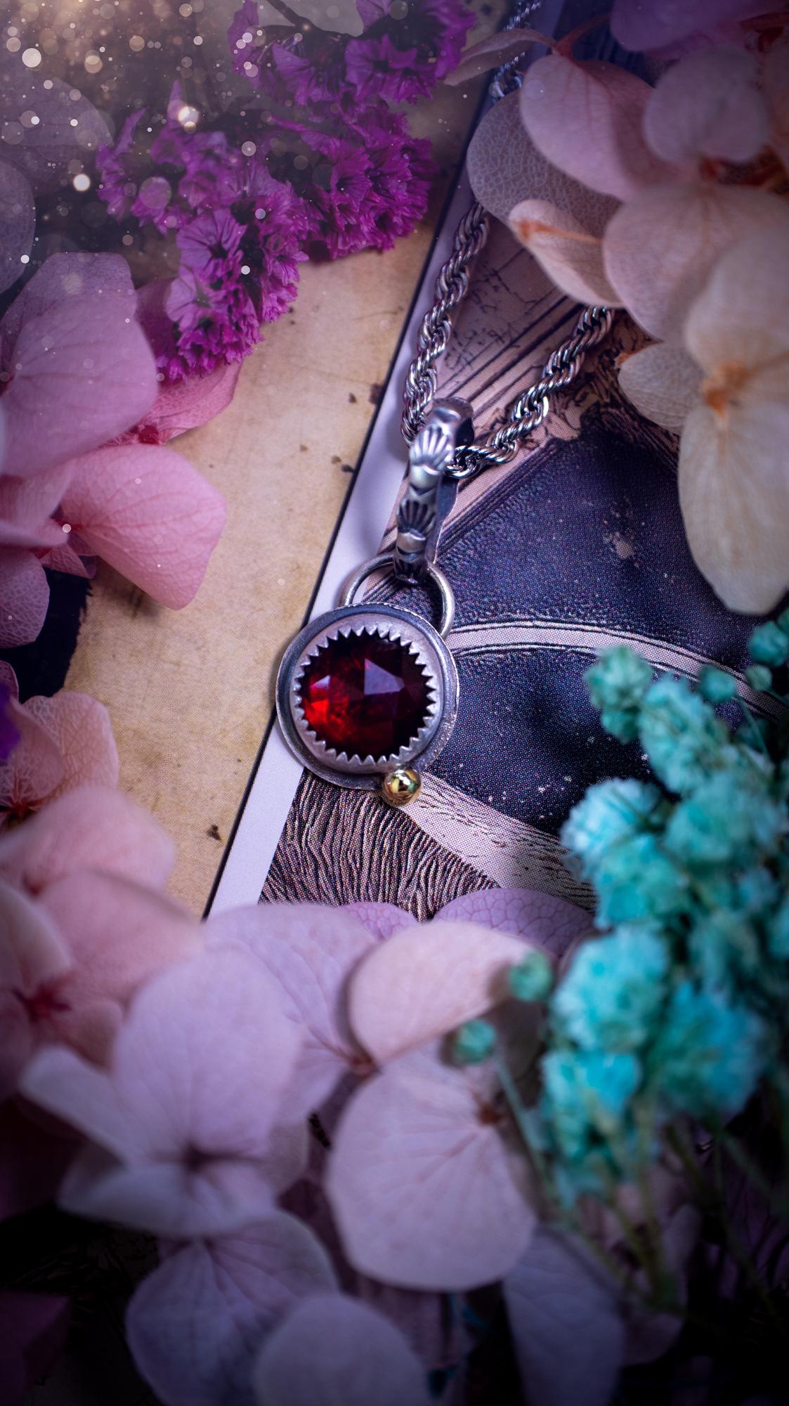 Handmade garnet pendant set in sterling silver with a satin brushed finish. The deep red natural garnet gemstone has a rich, wine-toned colour that catches the light beautifully. Finished with a polished brass golden ball accent and a decorative patterned bail. Gothic, bohemian and witchy style crystal jewellery, perfect as a meaningful gift or elegant everyday statement piece.