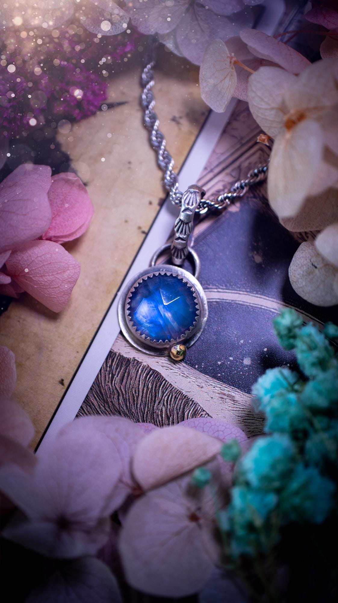 Handmade rainbow moonstone pendant set in sterling silver with a satin brushed finish. The natural moonstone gemstone shows a soft blue flash that shifts beautifully in the light. Finished with a polished brass golden ball accent and a decorative patterned bail. Bohemian, gothic and witchy style crystal jewellery, perfect as a unique gift or elegant everyday piece.