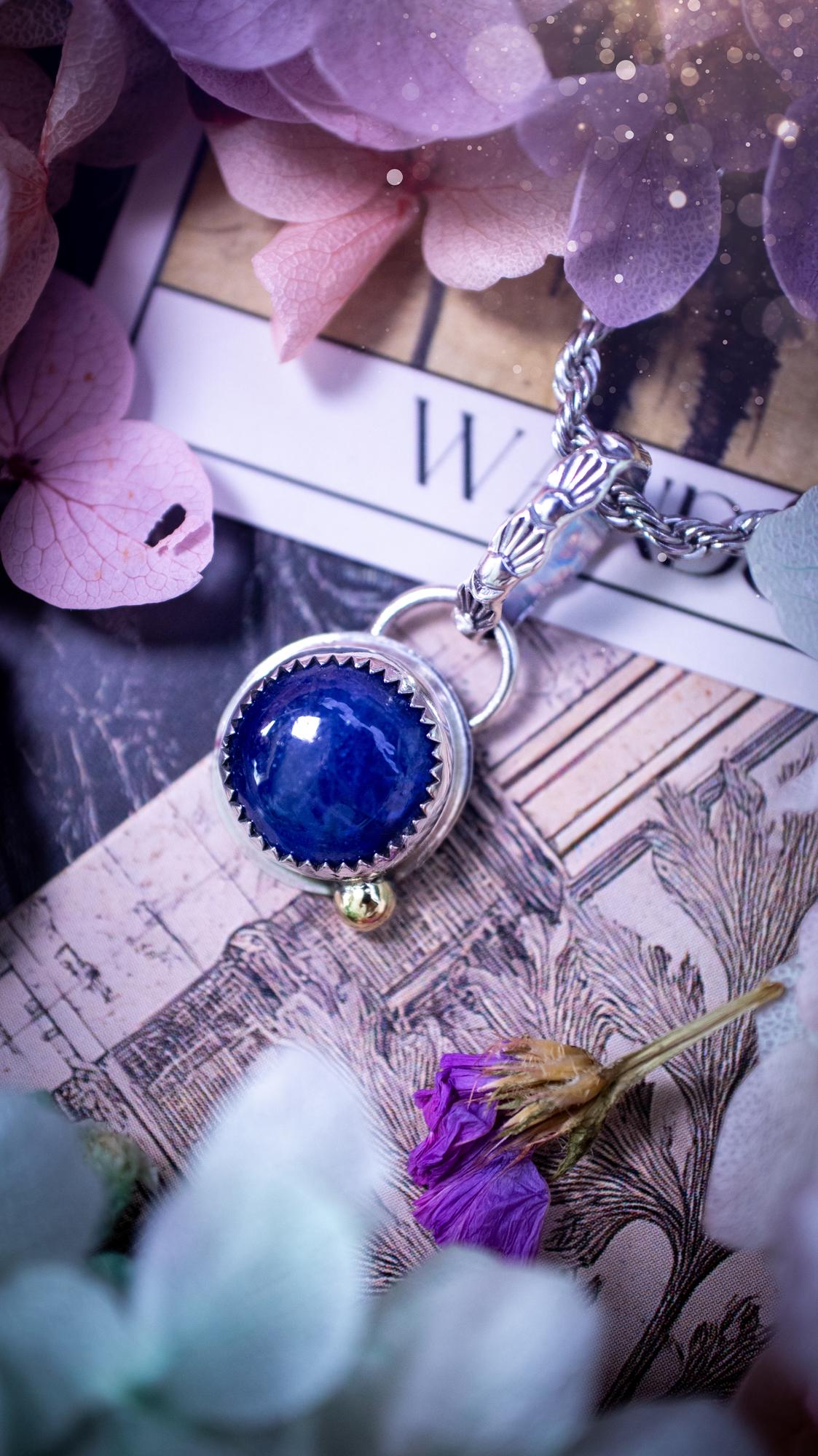 Handmade tanzanite pendant set in sterling silver with a high polished finish. The natural tanzanite gemstone displays rich blue violet tones with beautiful depth and shimmer in the light. Finished with a polished brass golden ball accent and a decorative patterned bail. Bohemian, gothic and witchy style crystal jewellery, perfect as a meaningful gift or elegant everyday statement piece. Tanzanite is the birthstone for December.