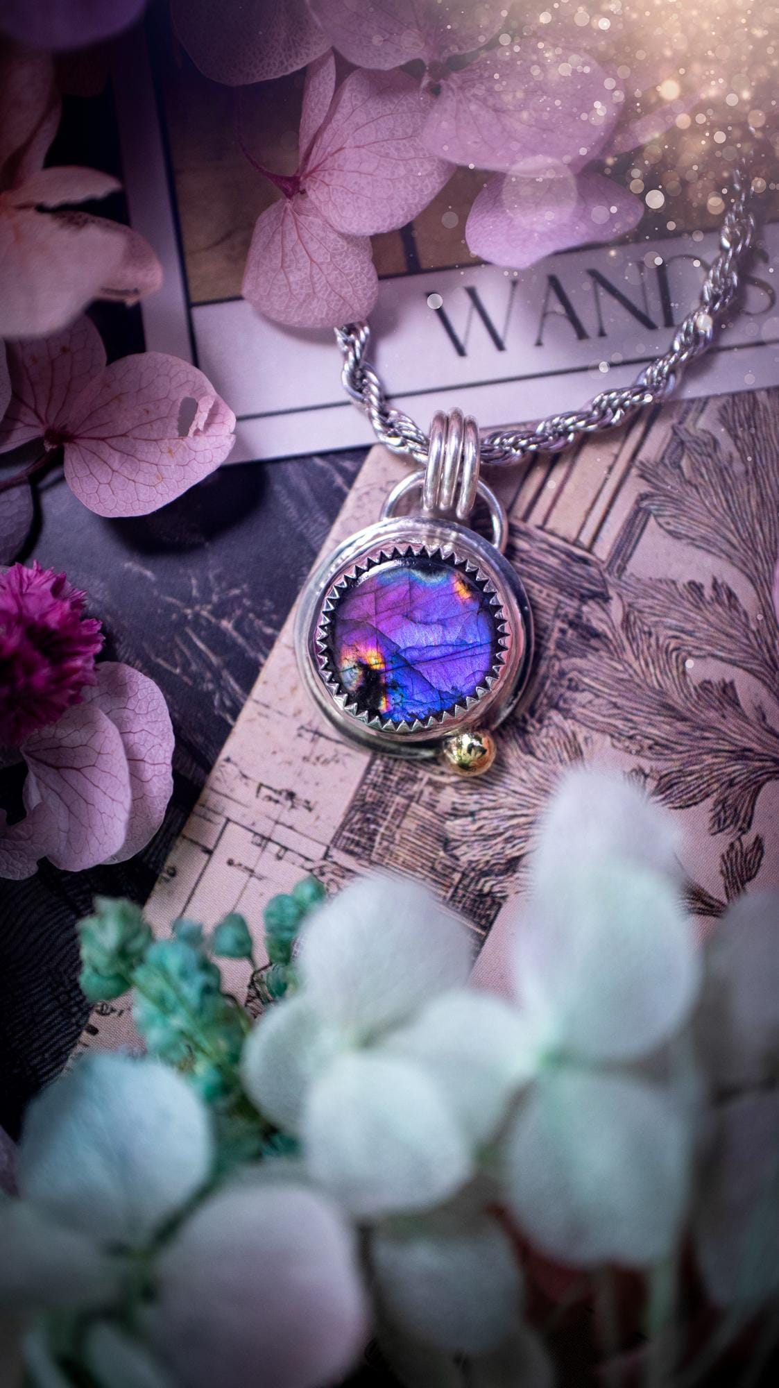 Handmade purple, rainbow labradorite pendant set in sterling silver with a high polished finish. The natural labradorite gemstone shows flashes of blue, gold and rainbow tones depending on the light. Features a polished brass golden ball accent and multi ring bail. Bohemian, gothic and witchy style crystal jewellery, perfect as a unique gift or everyday statement piece.