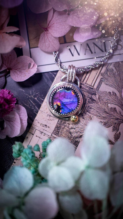 Handmade purple, rainbow labradorite pendant set in sterling silver with a high polished finish. The natural labradorite gemstone shows flashes of blue, gold and rainbow tones depending on the light. Features a polished brass golden ball accent and multi ring bail. Bohemian, gothic and witchy style crystal jewellery, perfect as a unique gift or everyday statement piece.