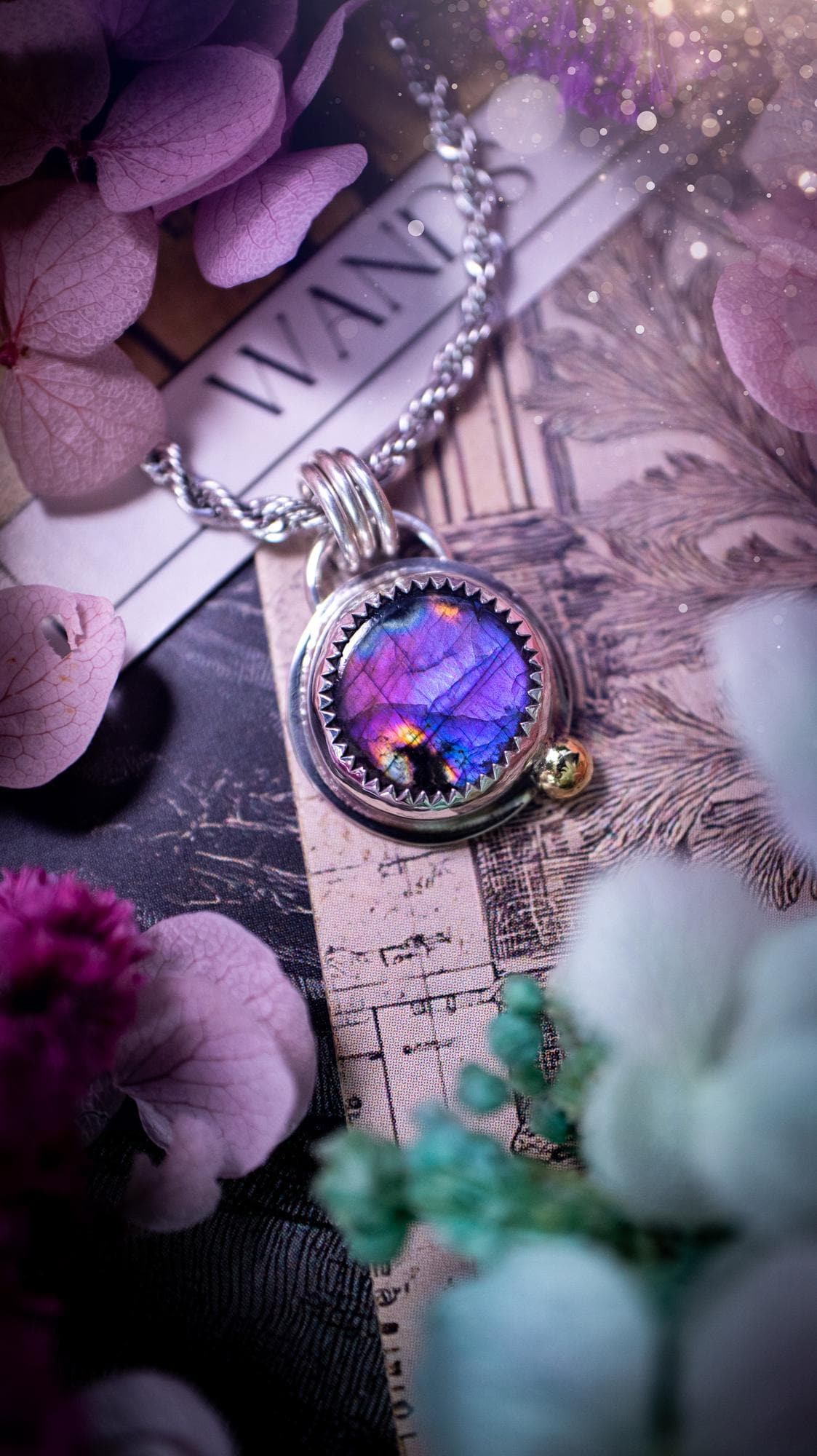 Handmade purple, rainbow labradorite pendant set in sterling silver with a high polished finish. The natural labradorite gemstone shows flashes of blue, gold and rainbow tones depending on the light. Features a polished brass golden ball accent and multi ring bail. Bohemian, gothic and witchy style crystal jewellery, perfect as a unique gift or everyday statement piece.