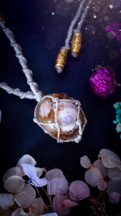 Handmade flower agate macrame pendant necklace featuring a natural patterned flower agate crystal in a woven caged design. Made using high quality Linhasita waxed cord with gold boho style accent beads. Bohemian, earthy and witchy inspired crystal jewellery, perfect for everyday wear or as a meaningful spiritual gift for crystal lovers.