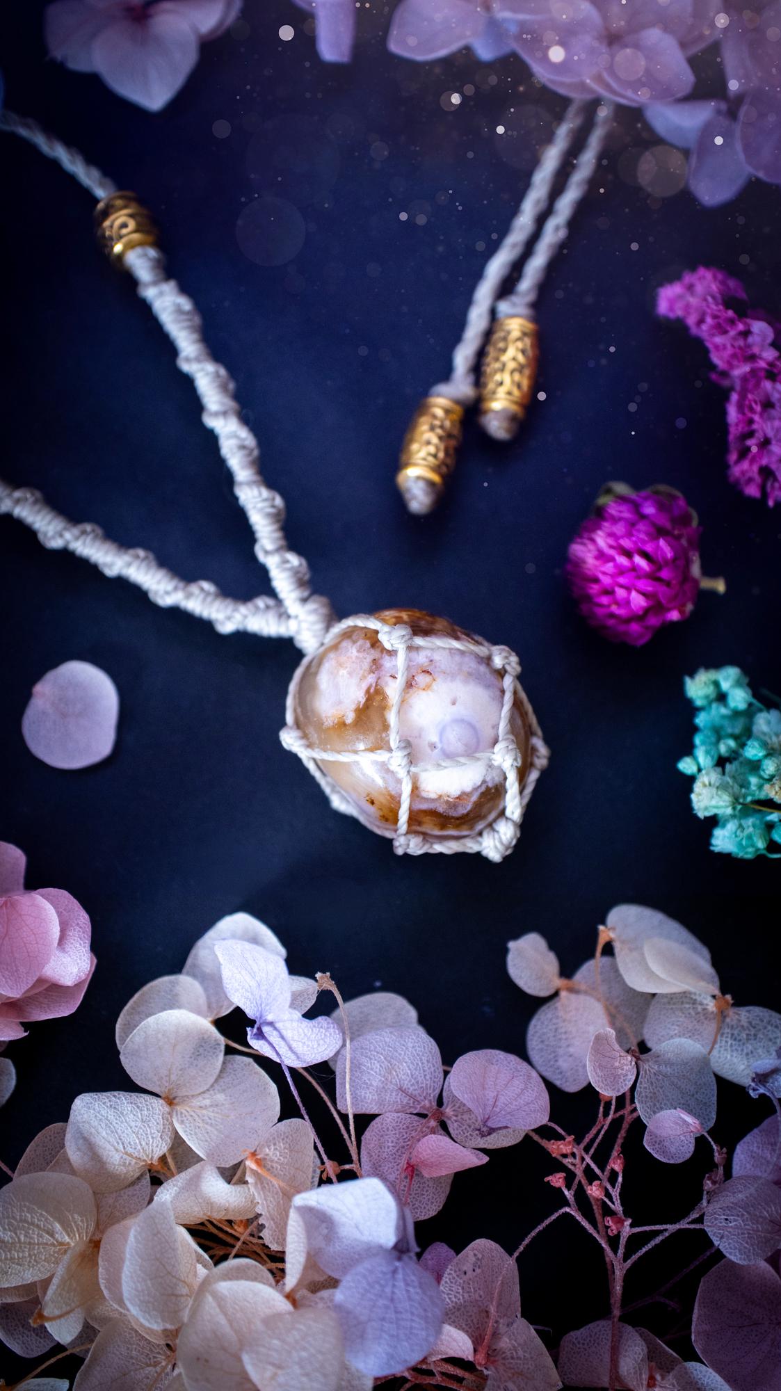 Handmade flower agate macrame pendant necklace featuring a natural patterned flower agate crystal in a woven caged design. Made using high quality Linhasita waxed cord with gold boho style accent beads. Bohemian, earthy and witchy inspired crystal jewellery, perfect for everyday wear or as a meaningful spiritual gift for crystal lovers.