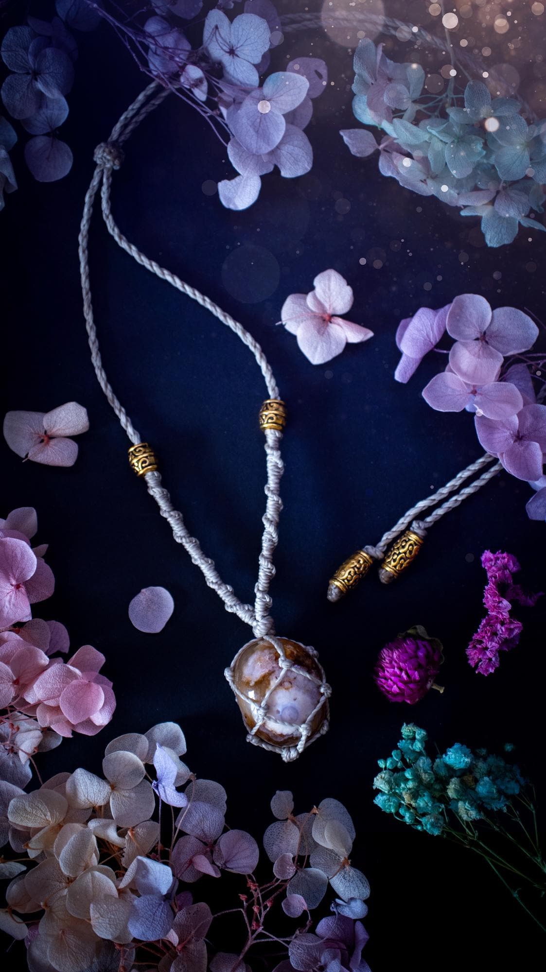 Handmade flower agate macrame pendant necklace featuring a natural patterned flower agate crystal in a woven caged design. Made using high quality Linhasita waxed cord with gold boho style accent beads. Bohemian, earthy and witchy inspired crystal jewellery, perfect for everyday wear or as a meaningful spiritual gift for crystal lovers.