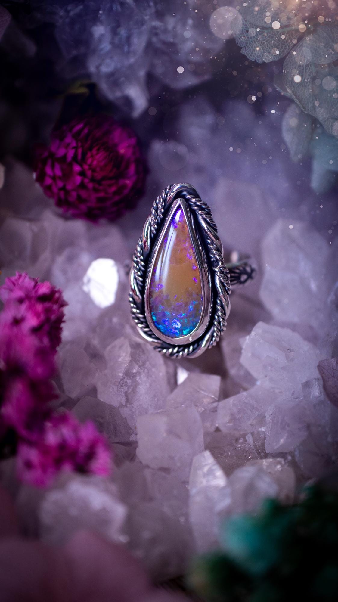 Handmade sterling silver and fine silver Australian opal ring displayed from an angled view. The natural opal shimmers with vivid pink, blue and purple colour play, surrounded by a smooth bezel setting. Decorative inner gallery wire and a hand-stamped patterned ring shank add artisan detail to this bold statement piece. UK size P, one-of-a-kind handmade jewellery.