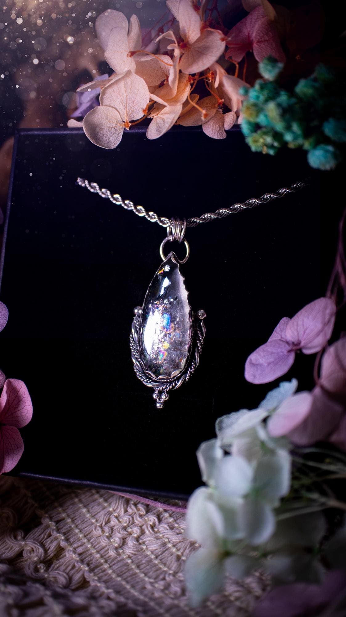 Handmade white topaz pendant necklace crafted from fine silver and sterling silver. The teardrop white topaz gemstone displays stunning natural cluster rainbows and subtle sparkle within the stone. The elegant silver setting highlights the crystal's unique inclusions and clarity. Photographed against a neutral background, this artisan gemstone necklace makes a thoughtful November birthstone gift. A necklace that is the definition of celestial and fairycore!