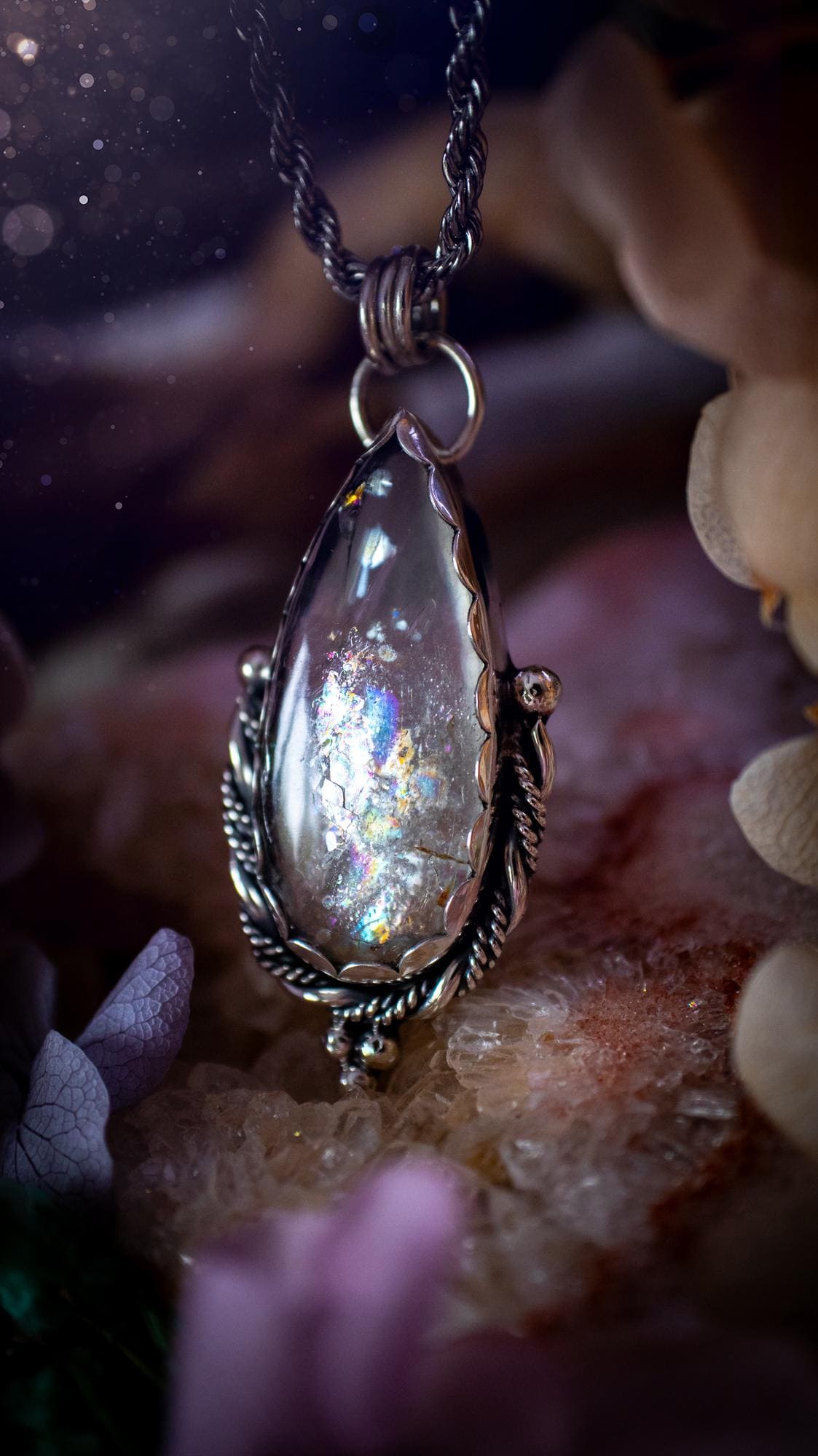 Handmade white topaz pendant necklace crafted from fine silver and sterling silver. The teardrop white topaz gemstone displays stunning natural cluster rainbows and subtle sparkle within the stone. The elegant silver setting highlights the crystal's unique inclusions and clarity. Photographed against a neutral background, this artisan gemstone necklace makes a thoughtful November birthstone gift. A necklace that is the definition of celestial and fairycore!