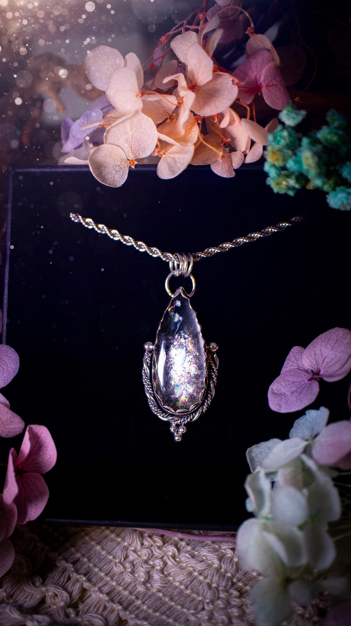Handmade white topaz pendant necklace crafted from fine silver and sterling silver. The teardrop white topaz gemstone displays stunning natural cluster rainbows and subtle sparkle within the stone. The elegant silver setting highlights the crystal's unique inclusions and clarity. Photographed against a neutral background, this artisan gemstone necklace makes a thoughtful November birthstone gift. A necklace that is the definition of celestial and fairycore!