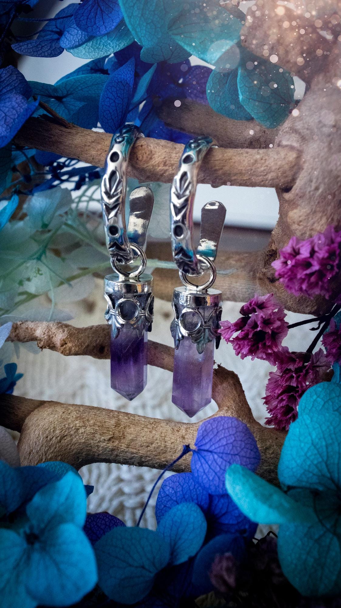 Handmade mini Amethyst point hoop earrings crafted from fine silver and sterling silver. Each natural purple Amethyst point is beautifully framed with ornate gothic gallery wire and suspended from hand-stamped sterling silver hoop earrings with textured detailing. Finished with secure butterfly backs, these artisan crystal earrings combine gothic, witchy and bohemian style. Elegant February birthstone jewellery, individually handcrafted with natural gemstones, making every pair completely unique
