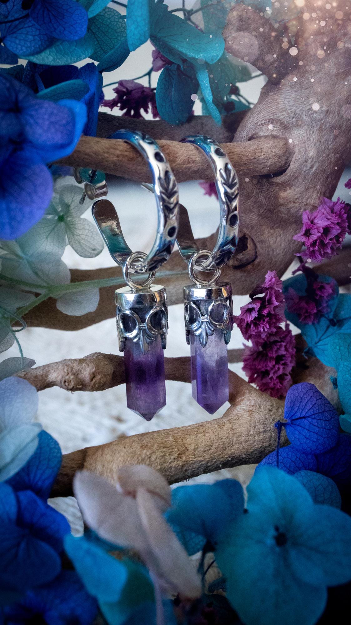 Handmade mini Amethyst point hoop earrings crafted from fine silver and sterling silver. Each natural purple Amethyst point is beautifully framed with ornate gothic gallery wire and suspended from hand-stamped sterling silver hoop earrings with textured detailing. Finished with secure butterfly backs, these artisan crystal earrings combine gothic, witchy and bohemian style. Elegant February birthstone jewellery, individually handcrafted with natural gemstones, making every pair completely unique