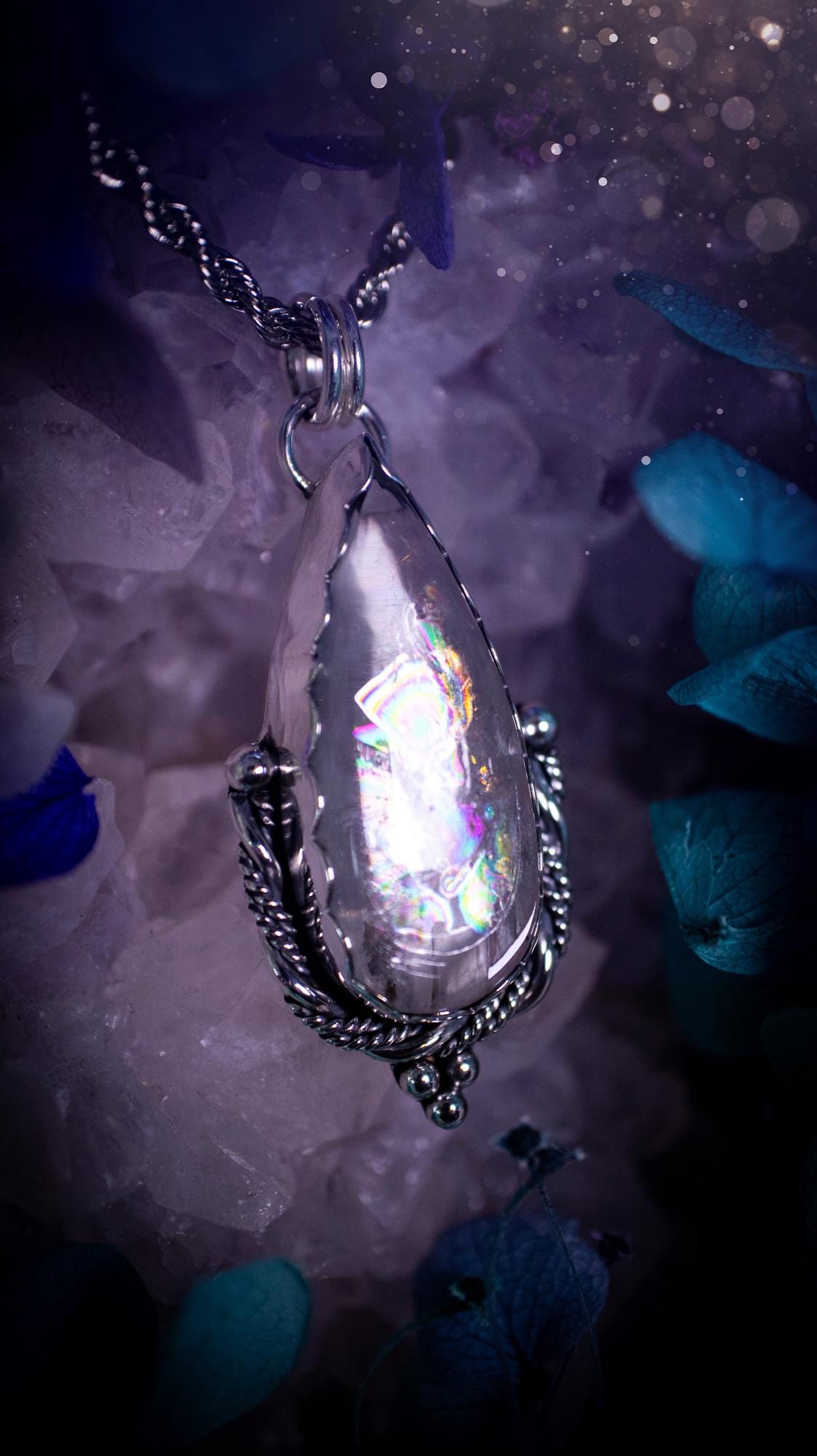 Handmade white topaz pendant necklace crafted from fine silver and sterling silver. The teardrop white topaz gemstone displays stunning natural cluster rainbows and subtle sparkle within the stone. The elegant silver setting highlights the crystal's unique inclusions and clarity. Photographed against a neutral background, this artisan gemstone necklace makes a thoughtful November birthstone gift. A necklace that is the definition of celestial and fairycore!