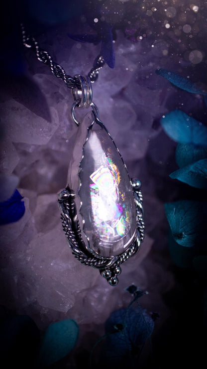 Handmade white topaz pendant necklace crafted from fine silver and sterling silver. The teardrop white topaz gemstone displays stunning natural cluster rainbows and subtle sparkle within the stone. The elegant silver setting highlights the crystal's unique inclusions and clarity. Photographed against a neutral background, this artisan gemstone necklace makes a thoughtful November birthstone gift. A necklace that is the definition of celestial and fairycore!