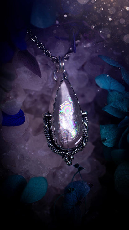 Handmade white topaz pendant necklace crafted from fine silver and sterling silver. The teardrop white topaz gemstone displays stunning natural cluster rainbows and subtle sparkle within the stone. The elegant silver setting highlights the crystal's unique inclusions and clarity. Photographed against a neutral background, this artisan gemstone necklace makes a thoughtful November birthstone gift. A necklace that is the definition of celestial and fairycore!