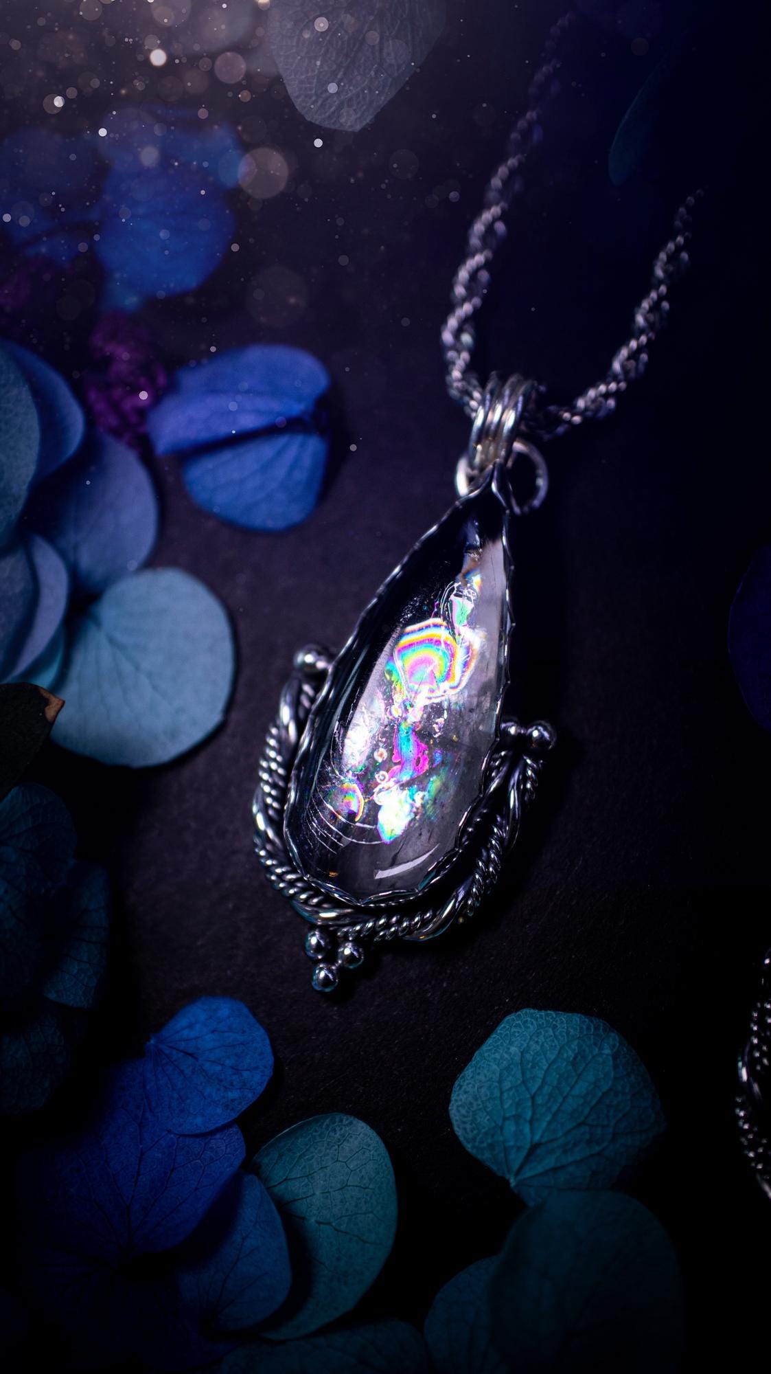 Handmade white topaz pendant necklace crafted from fine silver and sterling silver. The teardrop white topaz gemstone displays stunning natural cluster rainbows and subtle sparkle within the stone. The elegant silver setting highlights the crystal's unique inclusions and clarity. Photographed against a neutral background, this artisan gemstone necklace makes a thoughtful November birthstone gift. A necklace that is the definition of celestial and fairycore!