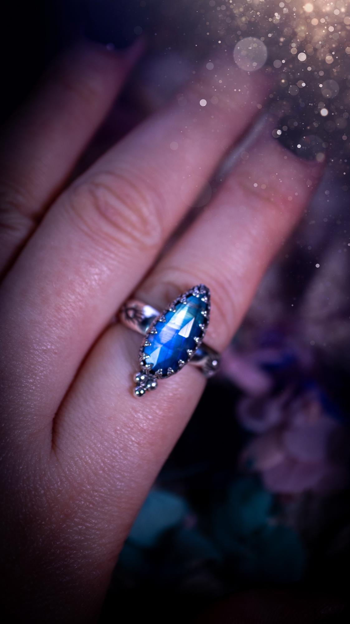 Beautiful and completely handmade, rainbow moonstone, gothic style mini statement stacker ring. This ring has been handcrafted using a mix of fine and sterling silver. Featuring a beautiful, high grade rainbow moonstone. The crystal is rose cut for a sparkle and is full of blue flash! Around the moonstone is a gothic gallery wire bezel, and little silver ball accents. The ring shank has a one of a kind stamped pattern. Ideal for birthdays and special occasions. Gothic and witchy jewellery.
