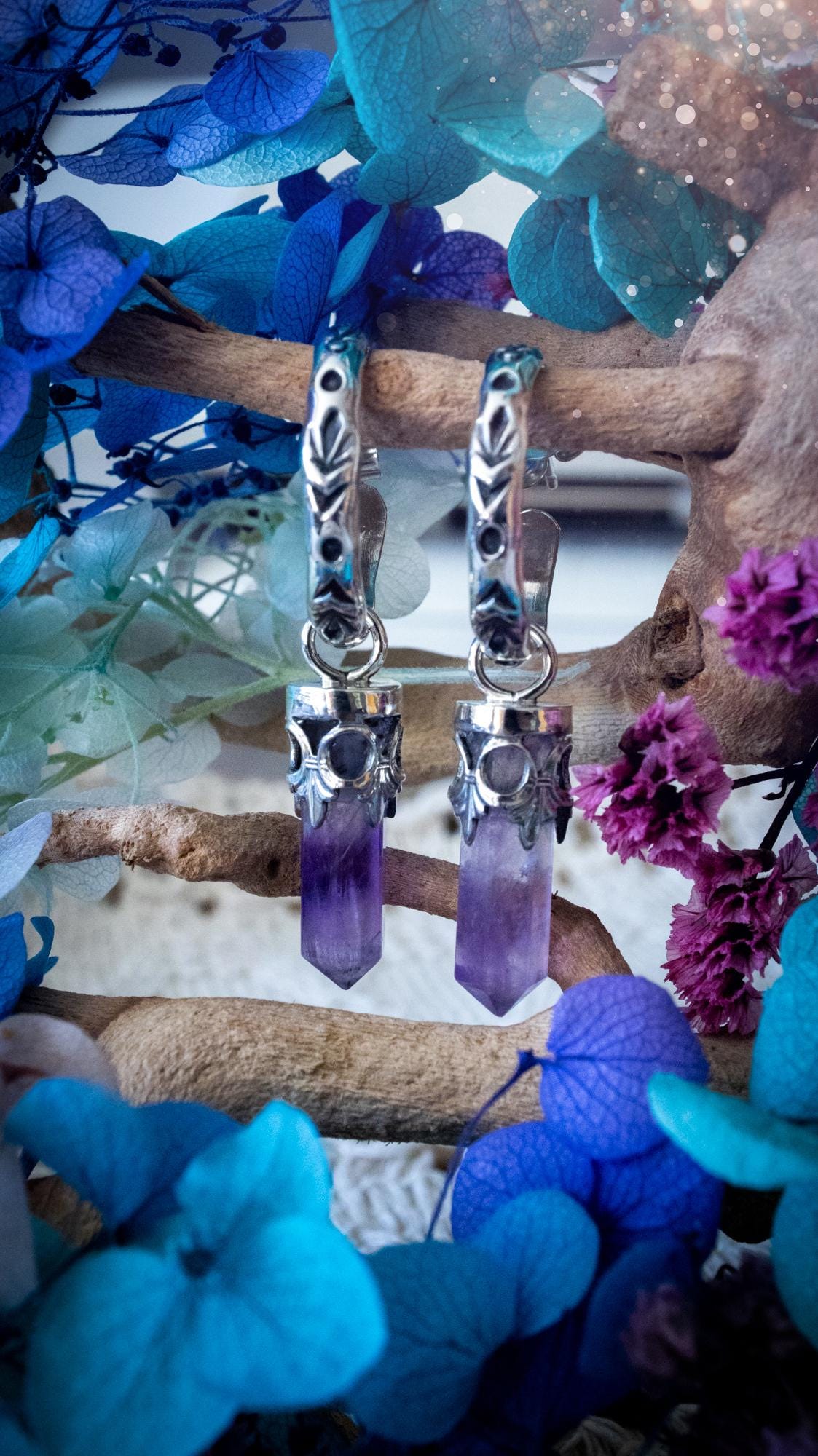 Handmade mini Amethyst point hoop earrings crafted from fine silver and sterling silver. Each natural purple Amethyst point is beautifully framed with ornate gothic gallery wire and suspended from hand-stamped sterling silver hoop earrings with textured detailing. Finished with secure butterfly backs, these artisan crystal earrings combine gothic, witchy and bohemian style. Elegant February birthstone jewellery, individually handcrafted with natural gemstones, making every pair completely unique