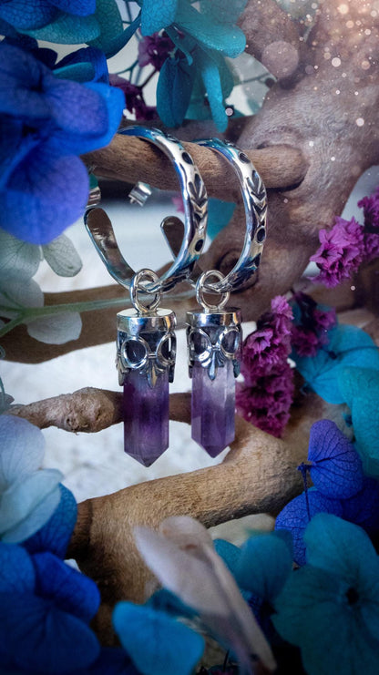 Handmade mini Amethyst point hoop earrings crafted from fine silver and sterling silver. Each natural purple Amethyst point is beautifully framed with ornate gothic gallery wire and suspended from hand-stamped sterling silver hoop earrings with textured detailing. Finished with secure butterfly backs, these artisan crystal earrings combine gothic, witchy and bohemian style. Elegant February birthstone jewellery, individually handcrafted with natural gemstones, making every pair completely unique