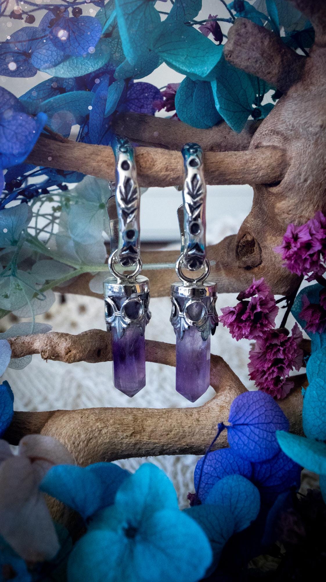 Handmade mini Amethyst point hoop earrings crafted from fine silver and sterling silver. Each natural purple Amethyst point is beautifully framed with ornate gothic gallery wire and suspended from hand-stamped sterling silver hoop earrings with textured detailing. Finished with secure butterfly backs, these artisan crystal earrings combine gothic, witchy and bohemian style. Elegant February birthstone jewellery, individually handcrafted with natural gemstones, making every pair completely unique