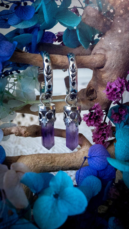 Handmade mini Amethyst point hoop earrings crafted from fine silver and sterling silver. Each natural purple Amethyst point is beautifully framed with ornate gothic gallery wire and suspended from hand-stamped sterling silver hoop earrings with textured detailing. Finished with secure butterfly backs, these artisan crystal earrings combine gothic, witchy and bohemian style. Elegant February birthstone jewellery, individually handcrafted with natural gemstones, making every pair completely unique